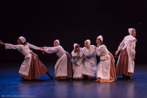 Several woman in early American clothes performing for Thw Witching Hour, at left one if pulling another by the arm to prevent her from going off. © Miceli Productions Photography