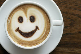 Happy coffee makes happy business meetings with Miceli Productions. Photo of a white coffee cup with a smily face in the latte foam.