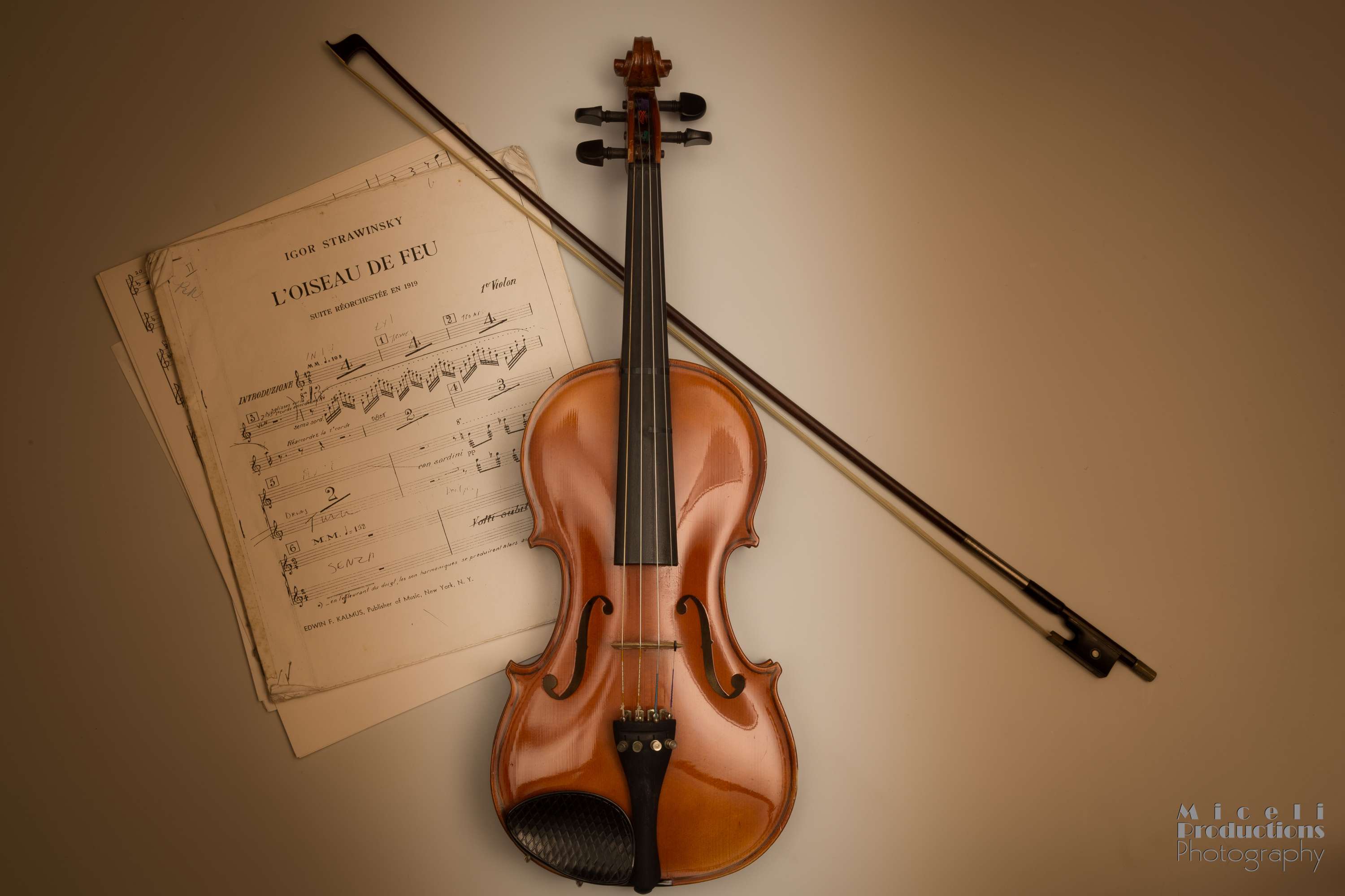 Violin with bow and sheet music on a tan background.