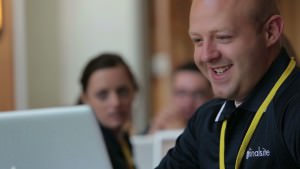 A Finalsite employee looks happily at a monitor during Finalsite University