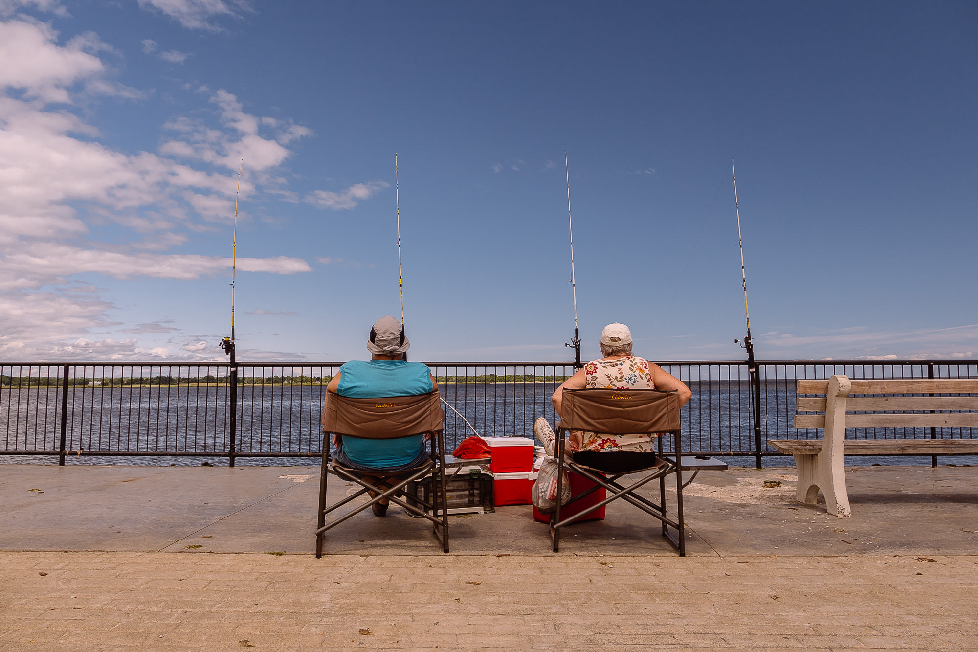 Two retired fishermen sit on the pier in Old Saybrook, Connecticut on shoreline CT during a beautiful day.