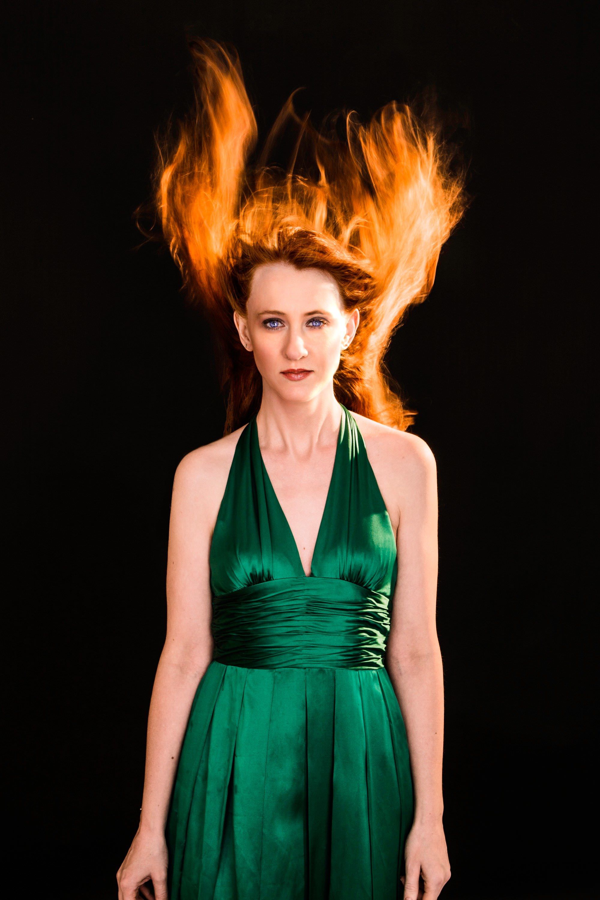 Woman with shocking red hair in a green dress in the same pose as Drew Barrymore in Firestarter. Photo by Miceli Productions