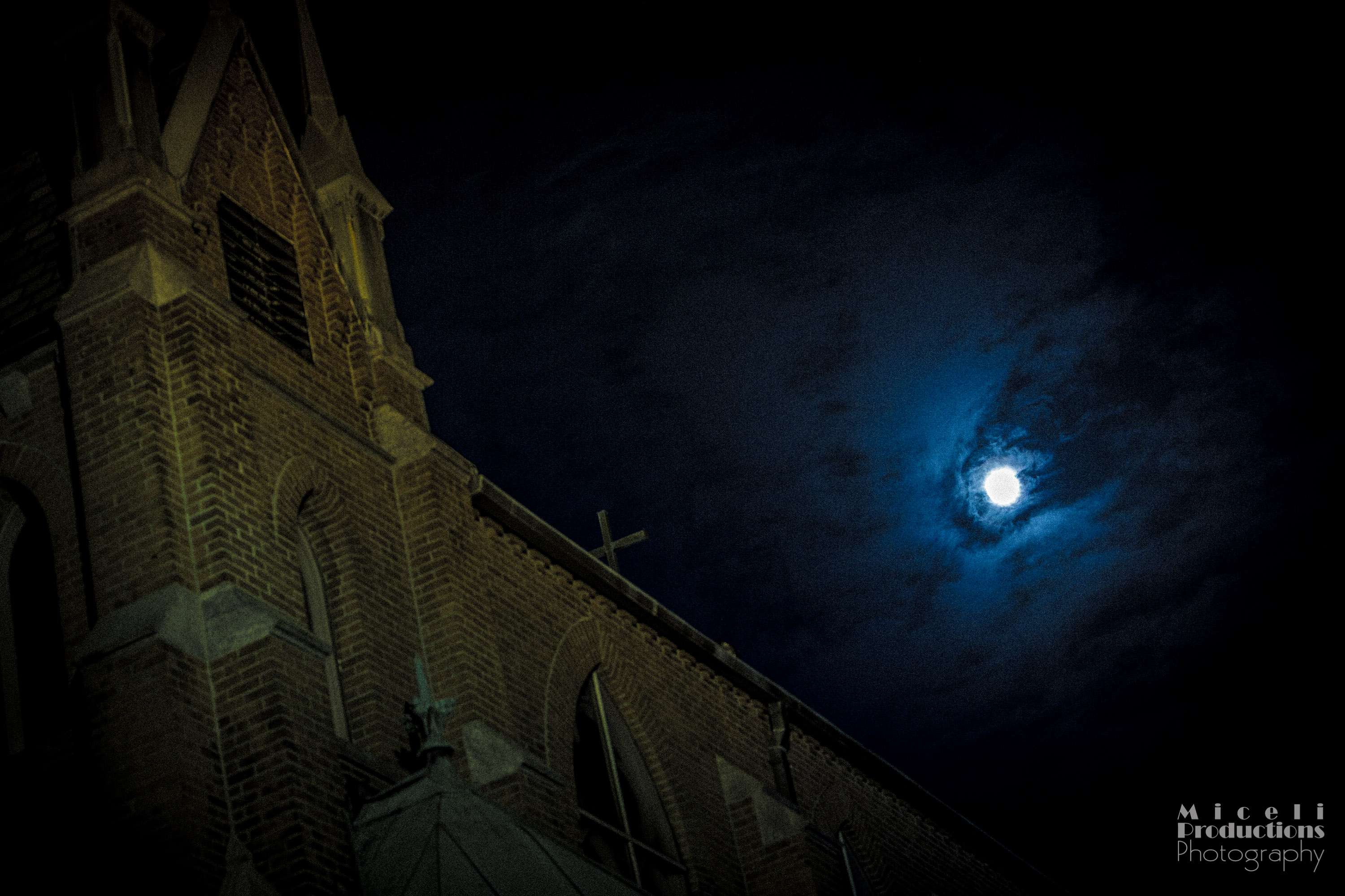 Supermoon illuminates church in Waterbury, CT. Gothic looking cathedral on the left with the moon in the cloud to the right of the image.