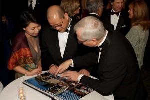 Company managers look through a custom photography book created for a retiring executive. 