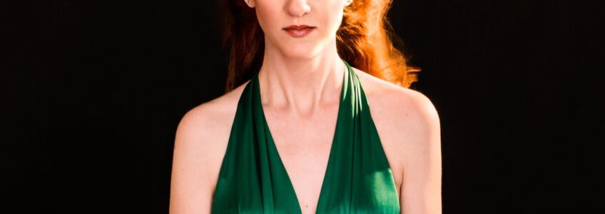 Woman with shocking red hair in a green dress in the same pose as Drew Barrymore in Firestarter. Photo by Miceli Productions