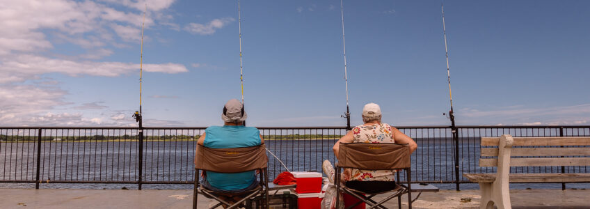 Two retired fishermen sit on the pier in Old Saybrook, Connecticut on shoreline CT during a beautiful day.