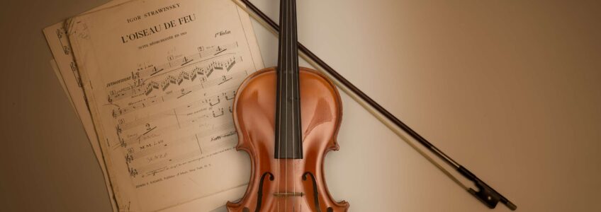 Violin with bow and sheet music on a tan background. Image by Miceli Productions, commercial photography in CT.