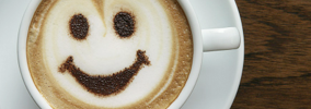 Happy coffee makes happy business meetings with Miceli Productions. Photo of a white coffee cup with a smily face in the latte foam.